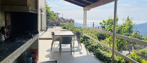 A covered patio with a table and chairs, a fireplace, and a view of a mountainous landscape.