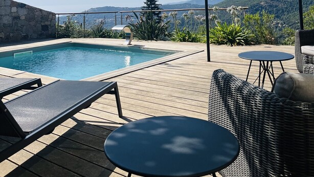 A pool area with a pergola, lounge chairs, and a table. - Charming house with sea and mountain views and private pool (Sari-d'Orcino)
