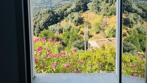 A window view of a mountainous landscape with greenery and pink flowers. - Charming house with sea and mountain views and private pool (Sari-d'Orcino)