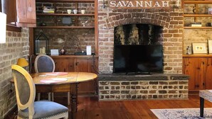 Un intérieur rustique avec une cheminée en briques, des étagères en bois et un coin repas.
