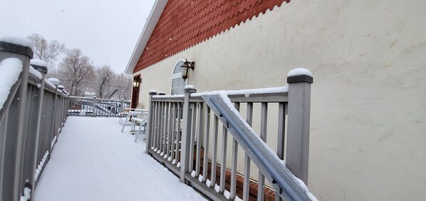 A snow-covered pathway leading to a building with a red roof and a brick entrance.