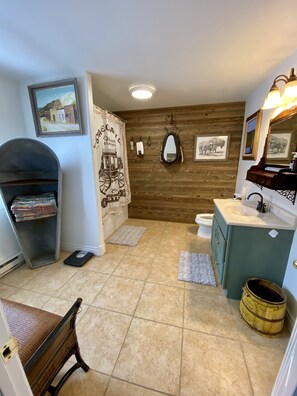 Une salle de bain avec un mur en bois, un lavabo, des toilettes, une balance et un miroir.