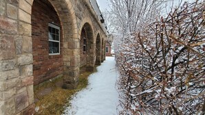 A stone building with arched windows and a snow-covered pathway. - Western Carriage House Studio Suite- Western themed retreat- Full Kitchen & Bath (Gillette)
