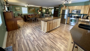 A spacious kitchen with wooden flooring, a central island, and modern appliances. - Western Carriage House Studio Suite- Western themed retreat- Full Kitchen & Bath (Gillette)