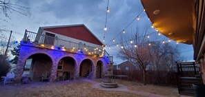 A building with a red roof, stone arches, and a balcony with string lights.