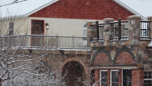 A brick building with a red roof and a stone balcony. - Western Carriage House Studio Suite- Western themed retreat- Full Kitchen & Bath (Gillette)