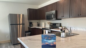 Una cocina moderna con gabinetes de madera oscura, electrodomésticos de acero inoxidable y encimera de mármol.
