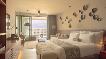 Una habitación de hotel moderna con una cama grande, una zona de estar con mesa y un balcón con vistas.