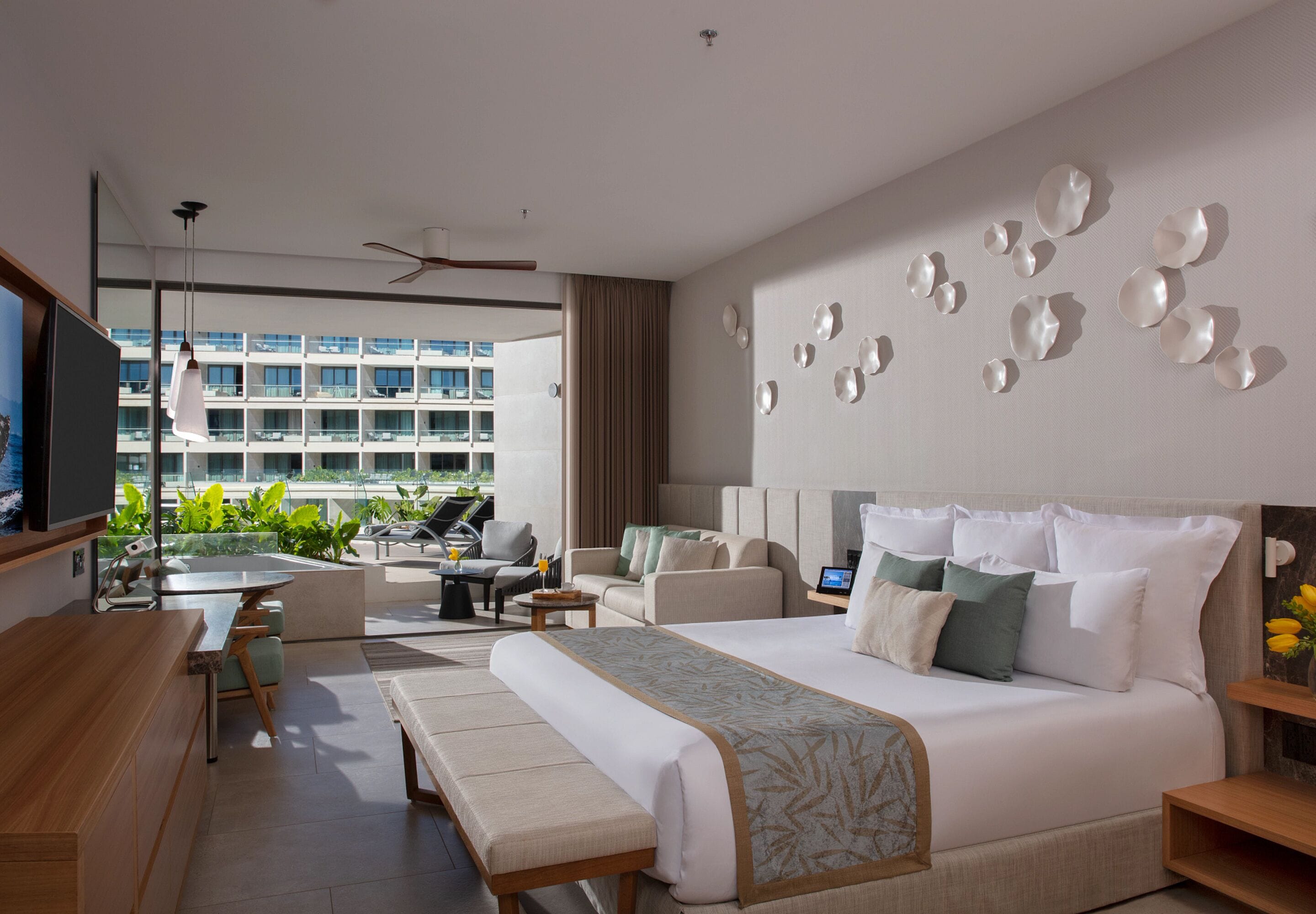 Habitación de hotel moderna con una cama grande, un escritorio y un área de descanso con vistas a la ciudad.