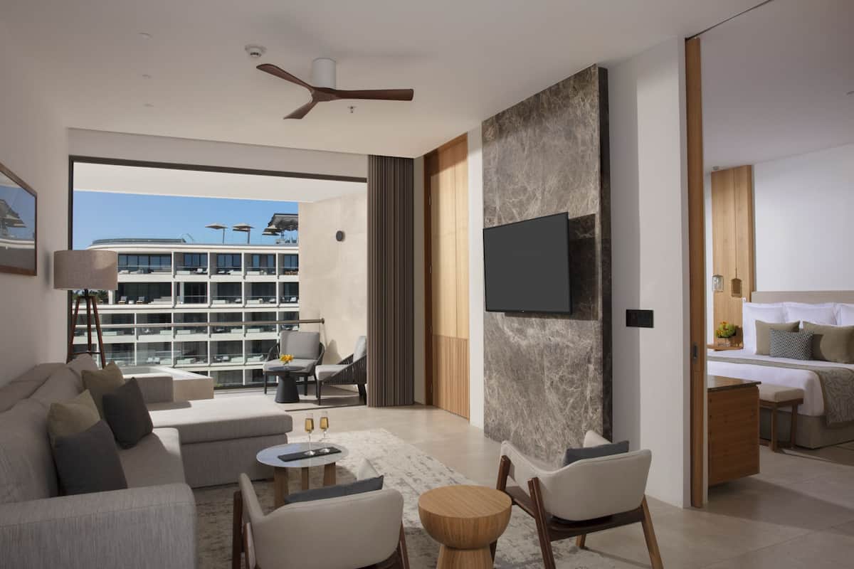 Una sala de estar moderna con un sofá, sillas, una mesa de centro y un televisor montado en la pared.
