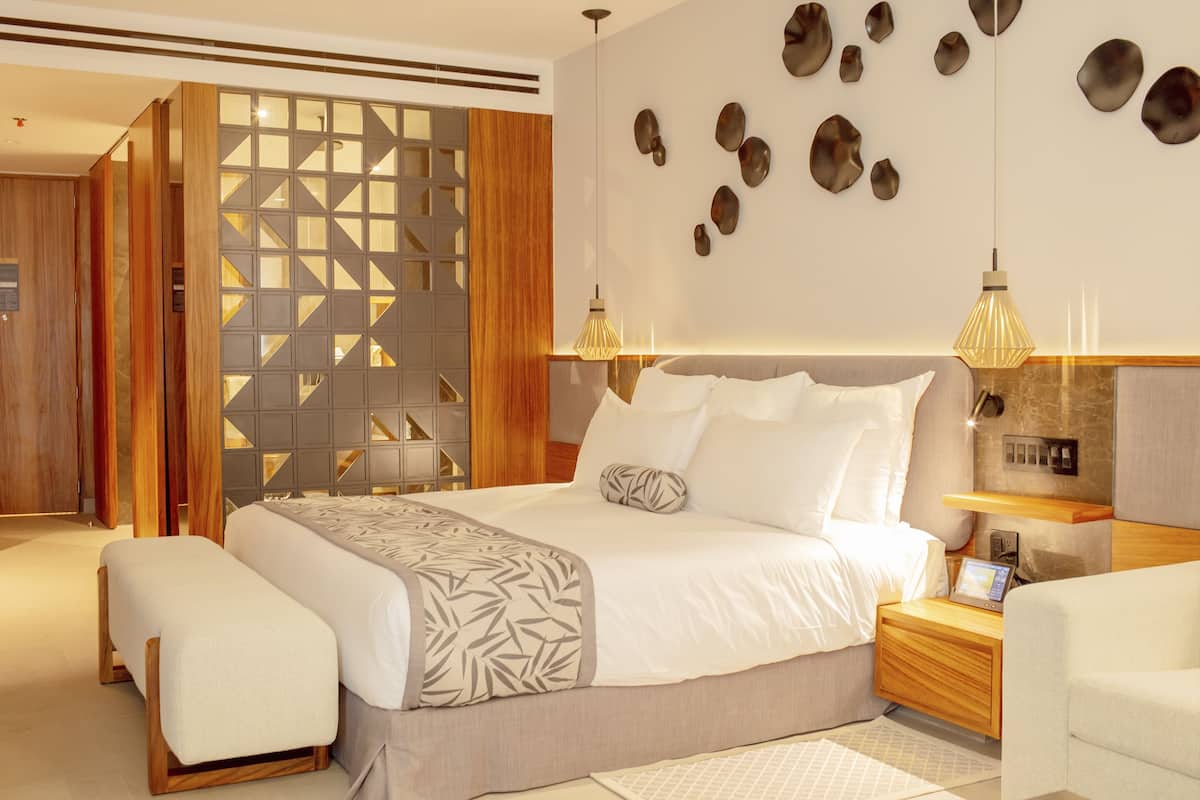 Un dormitorio moderno con una cama grande, mesitas de noche, un escritorio y un muro decorativo.