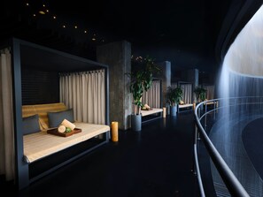 A modern interior with a bed, seating area, and a water feature.