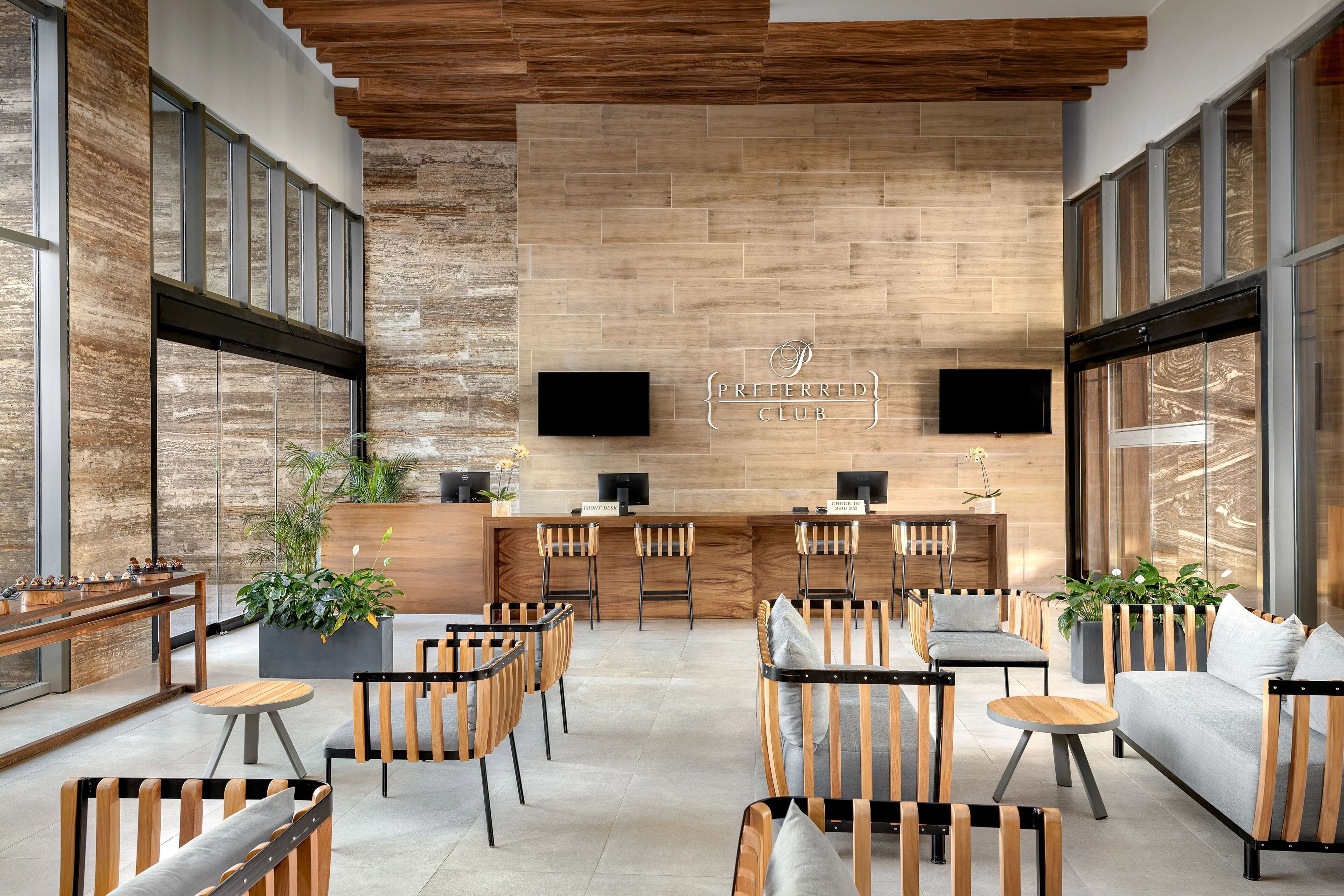 A modern lounge area with wooden furniture, a bar counter, and large windows.