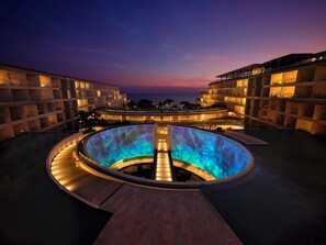 A hotel with a central pool area, multiple balconies, and a view of the ocean at dusk. - Secrets Bahia Mita Surf & Spa - Adults Only - All Inclusive (Punta de Mita)