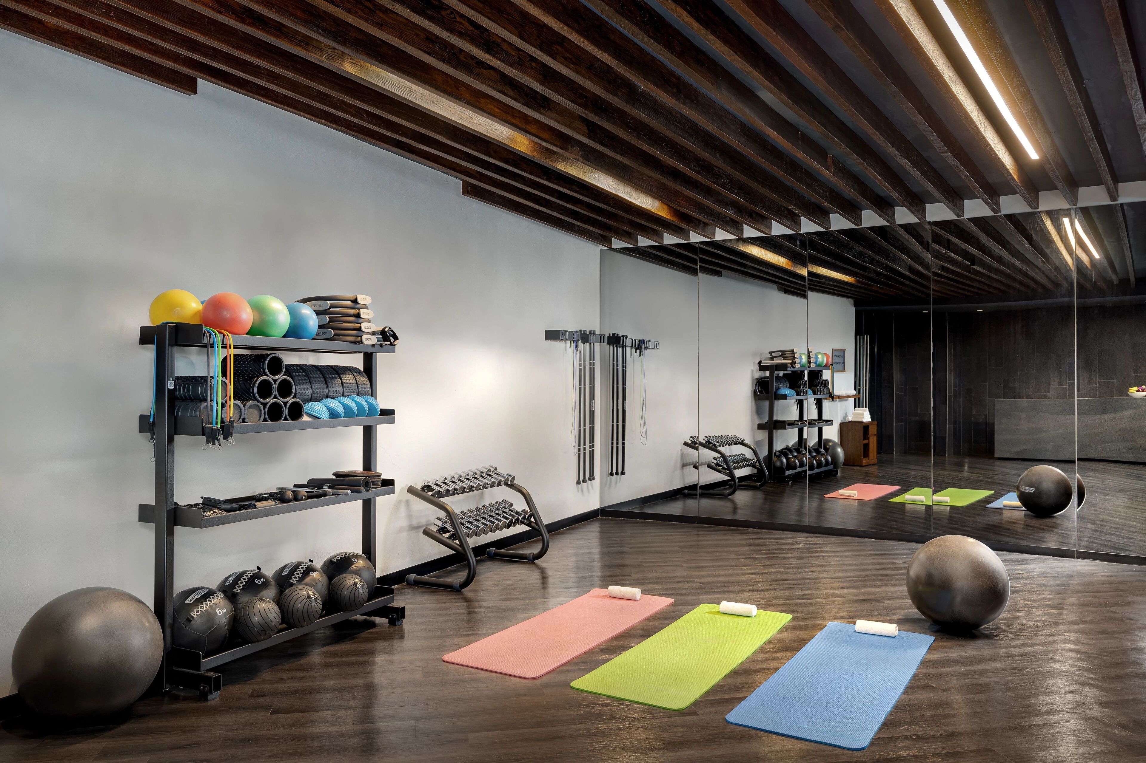 A gym with exercise equipment, mats, and a large mirror.