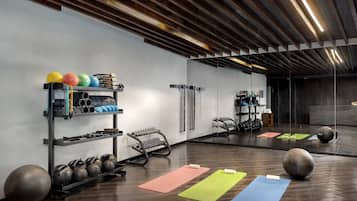 A gym with exercise equipment, mats, and a large mirror.