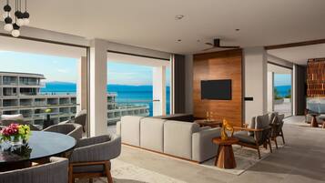 Una sala de estar moderna con un ventanal grande que da a un balcón y vistas al mar.