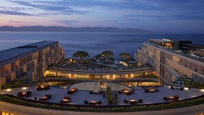 A modern hotel with a rooftop terrace, multiple floors, and a view of the sea.