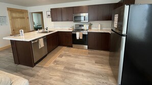 Una cocina moderna con armarios de madera oscura, electrodomésticos de acero inoxidable y encimera de mármol.