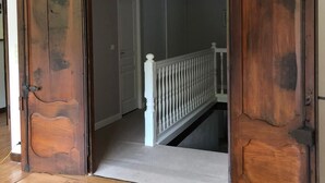 Un couloir avec des portes en bois et une rambarde blanche.