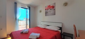 Une chambre à coucher avec un lit, une fenêtre avec des rideaux, un tableau au mur et une chaise.