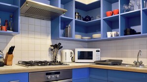 Une cuisine avec des meubles de couleur bleue, un four à micro-ondes, une cuisinière à gaz et un évier.