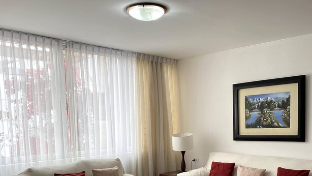A living room with two white sofas, one with red cushions, a wooden coffee table, a floor lamp, and a framed picture on the wall.