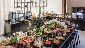 A buffet setup with various food items, a coffee machine, and a decorative plant centerpiece. - Clarion Hotel Sundsvall (Sundsvall)