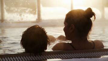A person in a hot tub with a view of the sunset.