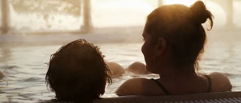 A person in a hot tub with a view of the sunset.