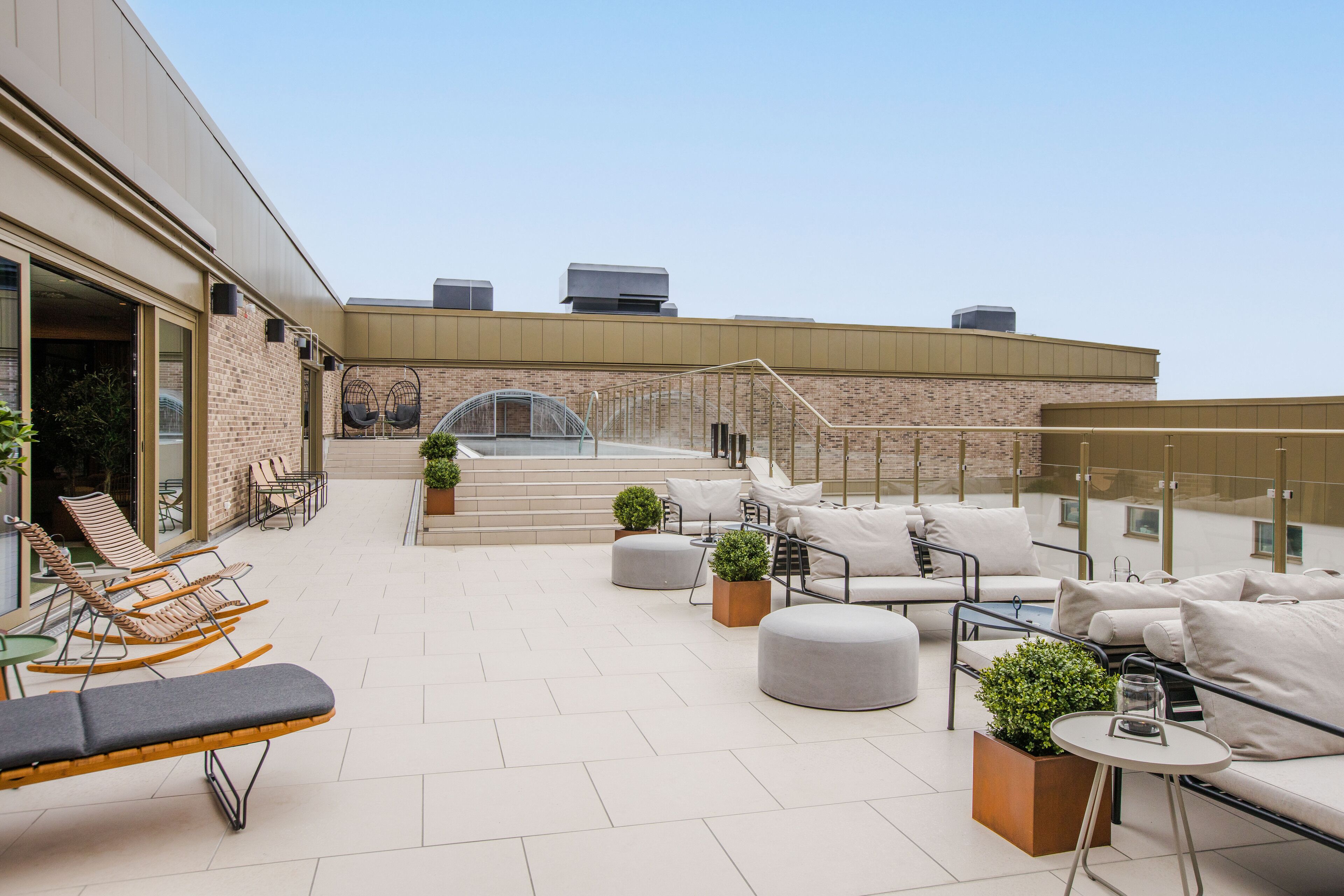 Terraza en la azotea con sillones, un espacio de descanso y plantas en macetas.