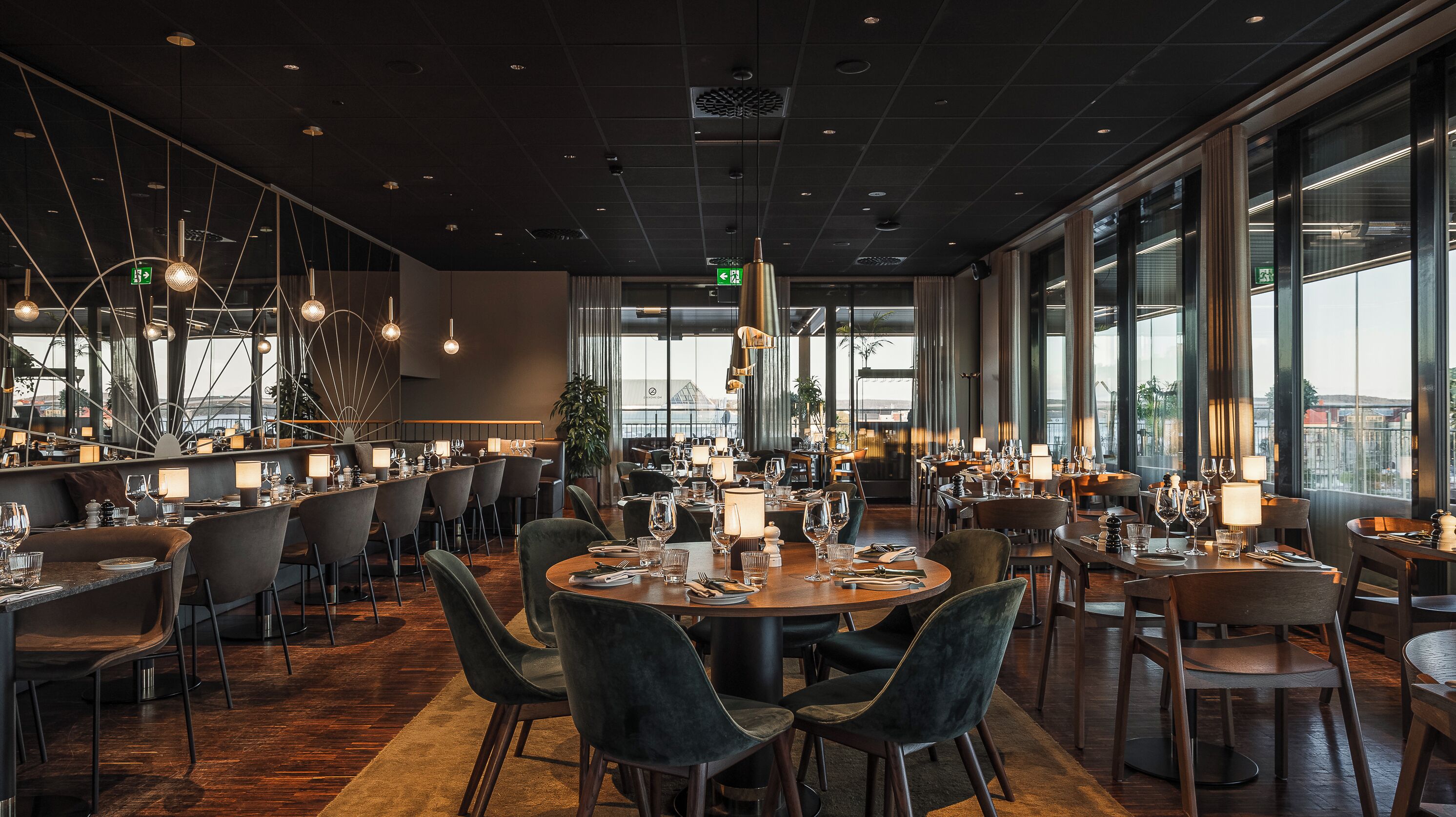A spacious restaurant with multiple dining areas, large windows offering views, and modern lighting fixtures.