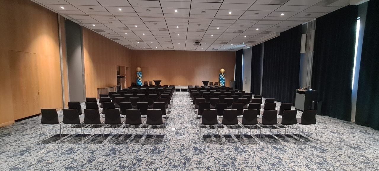 A conference room with rows of chairs and a stage.