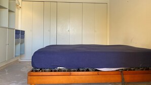 A bedroom with a bed, a wardrobe, and a small table. - L'Aminèxe - simple quiet under the stars in the fresh air (Tourrettes-sur-Loup)