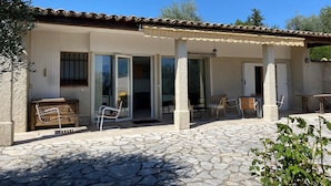 A building with a tiled roof, a covered patio area with outdoor furniture, and a stone-paved entrance. - L'Aminèxe - simple quiet under the stars in the fresh air (Tourrettes-sur-Loup)