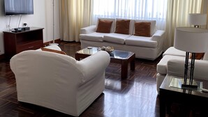 A modern living room with a sofa, a coffee table, a TV, and a lamp.