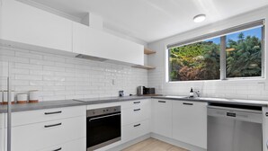 A modern kitchen with white cabinets, a stainless steel oven, and a dishwasher.