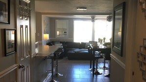 Eine Küche mit Kochinsel, ein Essbereich mit Sofa und eine Bar mit Hockern.