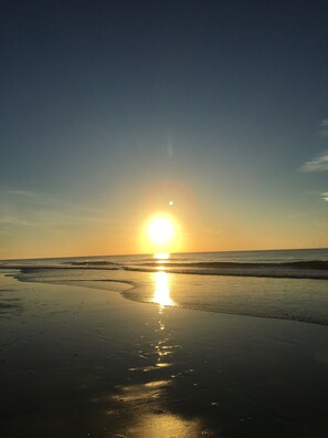 A beach scene with the sun setting over the ocean, reflecting on the wet sand. - 2nd Row 2 bed/1 bath Beach and Inlet property. Pet friendly with fee.  (Murrells Inlet)