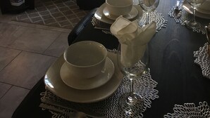 Ein Essbereich mit einem für vier Personen gedeckten Tisch, einer schwarzen Ledersofa und gerahmten Kunstwerken an den Wänden.