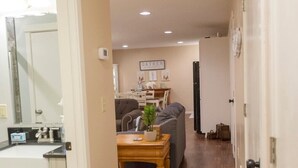 A hallway with a wooden floor, a kitchen area with a sink and cabinets, a dining table with chairs, and a gray sofa. - 2 Bedroom Oasis! Mother in-Law Apt Forest Lake, MN (Forest Lake)
