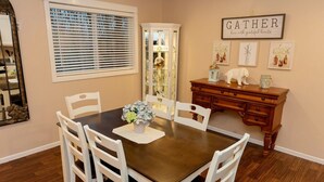 A dining room with a wooden table and white chairs, a cabinet with glass doors, and a wall-mounted sign that reads "GATHER here with grateful hearts". - 2 Bedroom Oasis! Mother in-Law Apt Forest Lake, MN (Forest Lake)