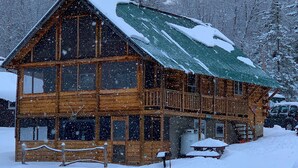 A wooden cabin with a green roof, surrounded by snow-covered trees. - Chalet Cabin,  Gore Skiing, Pool, AC, Spacious Cabin, Loon Lake (Chestertown)