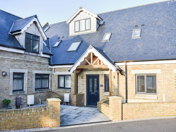 A two-story house with a dark roof, multiple windows, and a front door.