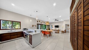 Une cuisine moderne avec un îlot central, un coin repas avec des chaises et un mur en bois.