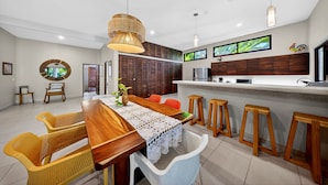 Una cocina moderna con una isla de madera, taburetes de bar y un comedor con sillas de mimbre.