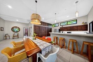 A modern kitchen with a wooden island, bar stools, and a dining area with wicker chairs.