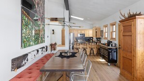 Un vaste espace dédié à la salle à manger, avec une longue table en bois, un banc rembourré et un éclairage moderne.
