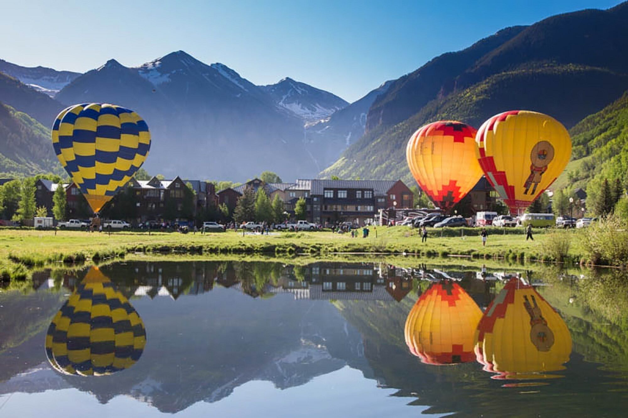 Un lago con globos aerostáticos y una montaña al fondo.