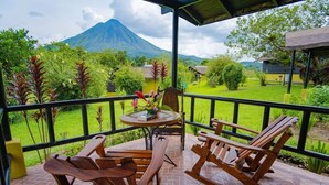 A wooden rocking chair and table set on a patio with a mountain view. - Campo Verde (La Fortuna)